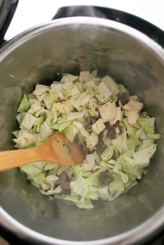 Add the cabbage to the cooked sausage and onions